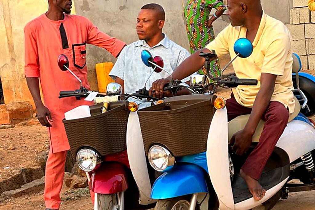 Two electric mobility scooters handed over in Magongo, with community members standing alongside