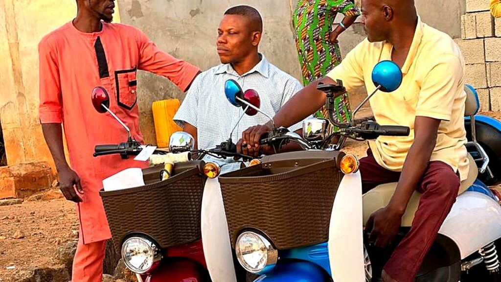 Two mobility scooters handed over to beneficiaries in Magongo, with community members standing alongside them
